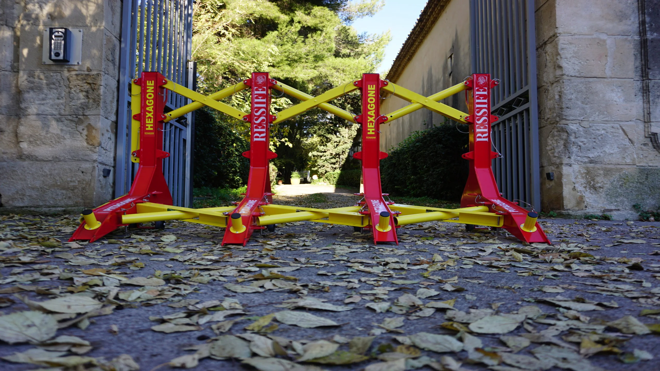 Barrière anti-bélier mobile Pitagone F18 rouge et jaune déployée devant un portail en milieu urbain